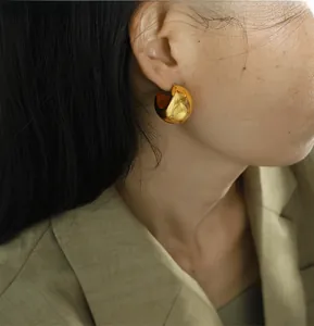 Close-up of a model wearing a chunky gold bean earring with a polished mirror finish