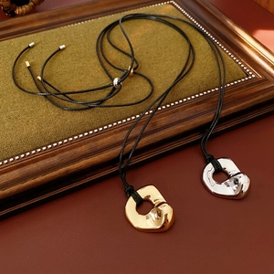 Minimalist irregular liquid metal ring pendants on black cords in gold and silver finish