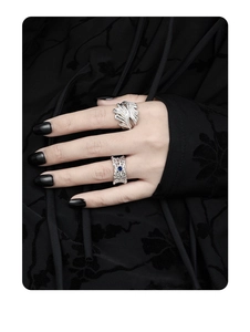Close-up of woven hollow silver ring with blue zircon inlay and feather design ring