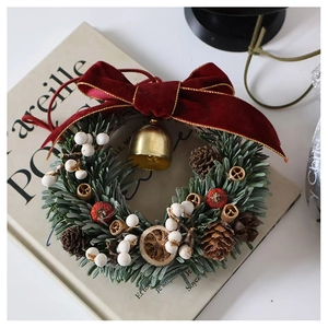 Macro detail of artificial pine needle wreath with red velvet bow and golden bell