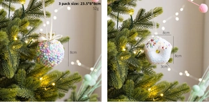 Close-up of pink foam Christmas ball and white donut ornament on a green festive tree