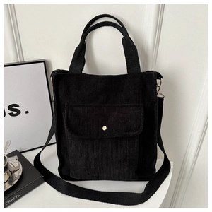 Detail of black corduroy tote bag featuring adjustable strap and metal snap pocket