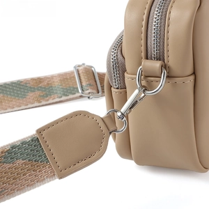 Dettaglio di hardware argento e tracolla jacquard su borsa a tracolla in pelle kaki