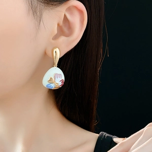Detail of vintage gold waterdrop earrings with colorful floral enamel patterns on a model