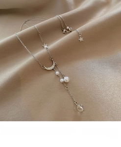 Detail of moon pendant pearl tassel necklace on champagne satin silk background