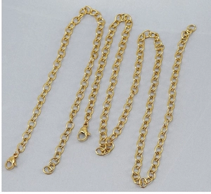 Detail shot of golden titanium steel link chains with lobster clasps on gray background