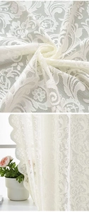 Detail of white lace curtain with delicate floral patterns and mesh texture on a window