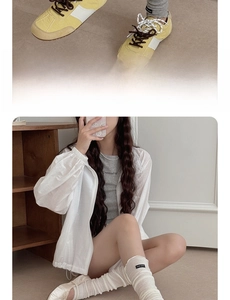Close-up of white summer sun protection jacket with drawstring hem and yellow retro sneakers