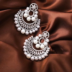 Detail of silver drop earrings with white pearls and sparkling cubic zirconia on silk