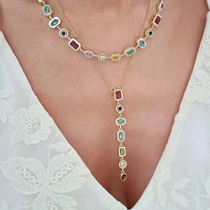 Elegant gold multilayer necklace featuring colorful gemstone charms on white lace