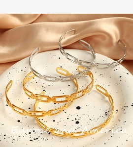 Detail of gold and silver chain link bangles on ceramic plate and beige silk fabric