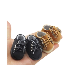 Mini doll boots in black and tan brown with plush lining held in hand for scale