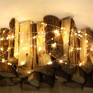 Luci LED in filo di rame con perle bianche decorative avvolte su tronchi rustici
