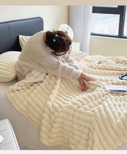 Detail of soft cream white faux fur blanket with 3D wavy textured pattern in bedroom