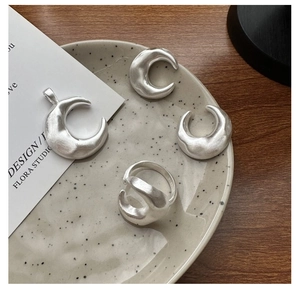 Macro detail of crescent moon pendant and ring with matte silver brushed finish
