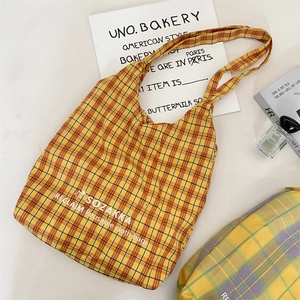 Detailed view of the yellow plaid canvas tote bag with logo and fashion props