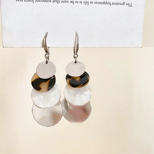 Detail of acrylic geometric round tiered earrings with tortoiseshell and pearl finish