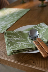 Dettaglio tovaglietta verde con motivo a foglie, trama lino e posate stile vintage