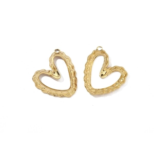 Detail of two gold-colored heart pendants with hammered metal texture and top rings