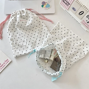Close-up of white polka dot drawstring bags with cosmetics and soft cotton texture