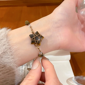 Detail showing handwoven bohemian bracelet with star-shaped tiger eye stone on a wooden desk