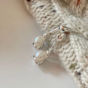 Detailed macro view of silver irregular teardrop earrings with white luminous pearls
