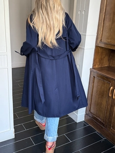 Vista posteriore di un trench blu navy con patta frangivento e dettaglio cintura in vita