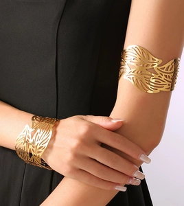 Close-up of a gold hollow leaf cuff bracelet worn on the arm showing metal texture