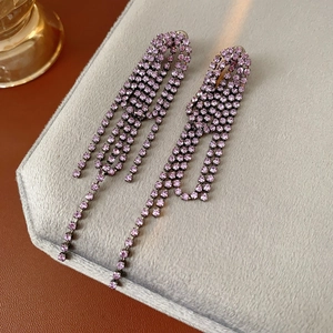 Detailed view of silver needle geometric earrings with purple crystal tassels on velvet