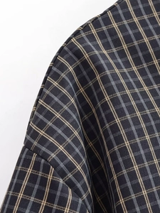 Gros plan sur la texture du tissu écossais noir et kaki et la couture de l'épaule