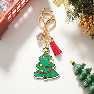 Close-up of Christmas tree keychain with red tassel and glitter globe on festive background