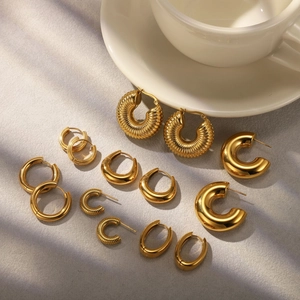 Detailed set of 7 pairs of gold-plated chunky and thin hoop earrings on a marble surface