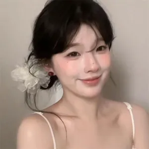 Detail showing elegant white camellia hair scrunchie with classic red ball stud earrings