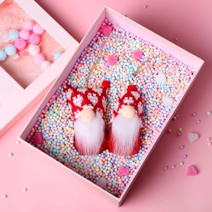 Detail of red and white knitted Christmas gnomes with heart patterns in a gift box
