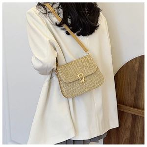 Detail of straw woven crossbody bag with gold horseshoe buckle and yellow leather strap