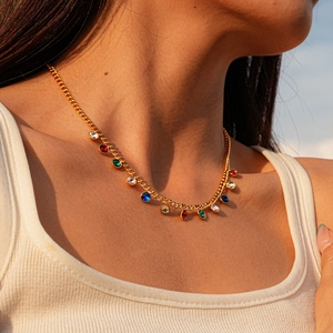 Detailed view of a gold sweater chain with vibrant colorful gemstone charms on model