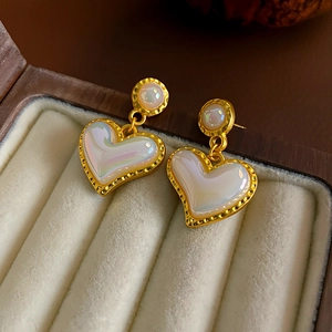 Detail of vintage heart-shaped earrings with iridescent finish in a cream velvet jewelry box