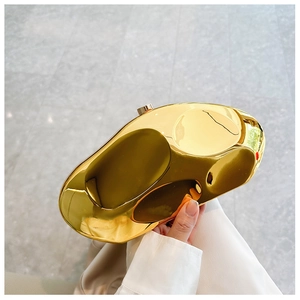 Close-up of golden bean-shaped metal clutch bag with polished finish and cylindrical clasp