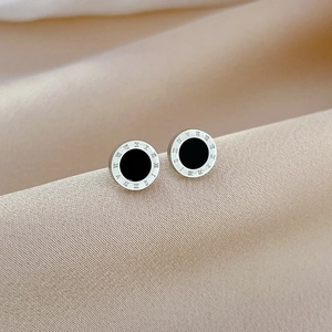 Close-up of titanium steel stud earrings with black shell and Roman numerals detail