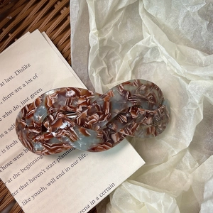 Detail of tortoise shell acetate twist hair clip placed on vintage book pages for retro style