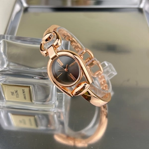 Macro shot of rose gold horsebit bracelet watch with a black Roman numeral dial