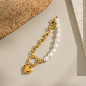 Detailansicht eines eleganten Gold-Herz-Perlenarmbandes mit Edelstahlkette für Damen