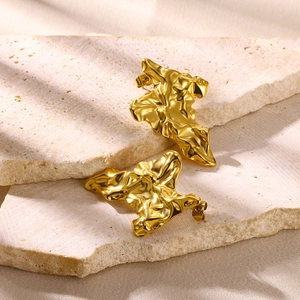 Detail of golden irregular flower earrings with crumpled metal texture on a stone pedestal
