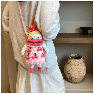Close-up of pink knit crossbody bag with cherry pattern worn by a model