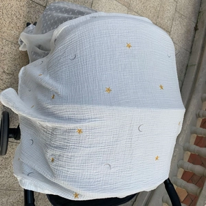 Detail of white breathable stroller cover featuring gold star and silver moon embroidery