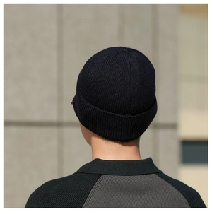 Vista posteriore di un berretto in maglia blu scuro indossato da un uomo su pietra