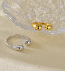Detail of minimalist S925 sterling silver open rings in gold and silver droplet design