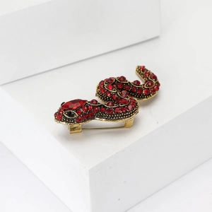 Macro shot of gold snake brooch featuring red rhinestones and polished metal finish