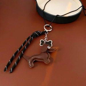 Detailed view of a brown leather dachshund pendant with bone charm on woven cord