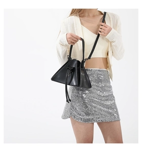 Detail of trendy black triangular crossbody bag with drawstring closure on model